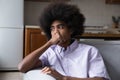 Pensive frustrated teenage African guy sitting on couch