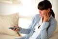 Pensive girl sitting on sofa using tv remote Royalty Free Stock Photo