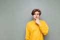 Pensive guy in casual clothes stands against a gray wall and looks away with reflections on copy space. Isolated