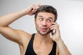 A pensive guy in singlet with smart phone Royalty Free Stock Photo