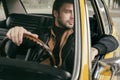 pensive handsome stylish man sitting in retro car and looking