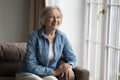 Pensive happy retired woman resting alone in cozy living room