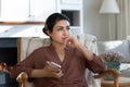 Pensive indian lady rest in armchair wait for phone call