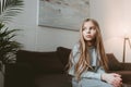 Pensive kid girl sitting on sofa alone Royalty Free Stock Photo