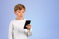 Pensive kid using smartphone on empty copy space background Royalty Free Stock Photo