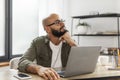 Pensive latin male freelancer thinking about something while working on laptop, sitting at desk and looking away Royalty Free Stock Photo