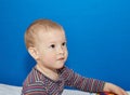 Pensive little baby on a blue background Royalty Free Stock Photo