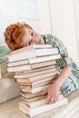 Pensive little boy leaning on pile on books Royalty Free Stock Photo