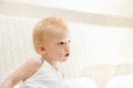 Pensive little boy sitting on white sofa Royalty Free Stock Photo