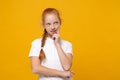 Pensive little ginger kid girl 12-13 years old in white t-shirt isolated on yellow wall background children studio Royalty Free Stock Photo