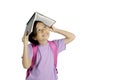 Pensive little girl putting a book on her head