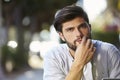 Pensive looking bearded young man sitting outside, portrait