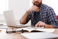 Close up of a serious man office worker is reading report, while is sitting at the table with open net-book. Royalty Free Stock Photo