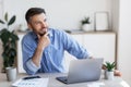 Pensive male entrepreneur thinking about something while working at desk in office