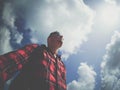 A pensive man against the background of clouds and sky, a man in glasses, a dreamy man, a young guy in a stylish shirt Royalty Free Stock Photo