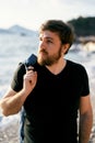 Pensive man with a denim jacket over his shoulder stands with his head turned to the side against the background of the Royalty Free Stock Photo