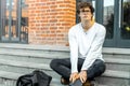 Pensive man sitting on steps of modern building and holding notepad in hands Royalty Free Stock Photo