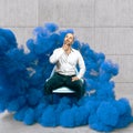 Pensive man sitting wrapped in blue smoke Royalty Free Stock Photo