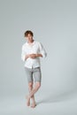 Pensive man standing full length folded arms and crossed legs. Thinking barefoot male model in white shirt demonstrates