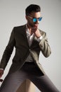 Pensive man wearing sunglasses and green suit sitting Royalty Free Stock Photo