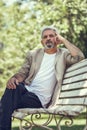 Pensive mature man sitting on bench in an urban park. Royalty Free Stock Photo