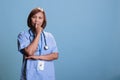 Pensive medical assistant wearing blue uniform thinking about health care treatment