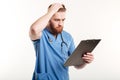 Pensive medical doctor or nurse with stethoscope looking at clipboard