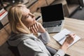 pensive middle aged woman taking notes and using laptop at home Royalty Free Stock Photo