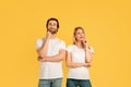 Pensive millennial caucasian male and woman in white t-shirts think and look up at empty space