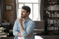 Pensive millennial entrepreneur touching chin in deep thoughts