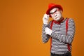 Pensive mime in red hat, white gloves and striped t-shirt on blank orange background Royalty Free Stock Photo