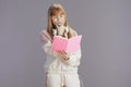 pensive modern pupil in beige tracksuit with workbooks