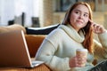 Pensive teenager girl with cup of hot beverage and laptop Royalty Free Stock Photo