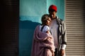 Pensive mulatto woman with trendy hairtyle and her dark skinned stylish boyfriend in red hat, stand close to each other