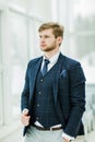 Pensive newcomer businessman in a business suit stands near a wi Royalty Free Stock Photo