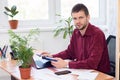 Pensive office specialist sits at a table in the office and looked into the frame