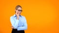 Pensive office worker looking camera on orange background, choice hesitation