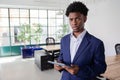 Pensive office worker standing in office and holding tablet