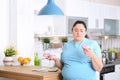 Pensive overweight woman with donuts in kitchen