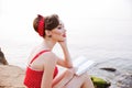 Pensive pin up girl sitting with book on the rock Royalty Free Stock Photo