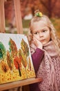 Pensive portrait of a child. little girl artist on the background of painted paintings in autumn in the park