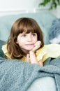 Pensive portrait of a little girl with blue eyes on the couch
