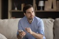 Pensive positive young man using mobile phone, sitting on couch Royalty Free Stock Photo