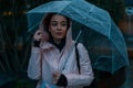 Pretty girl holding umbrella and strolling on rainy autumn day. photo looks like film frame or movie screenshot Royalty Free Stock Photo