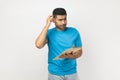 Pensive puzzled man standing with clipboard, writing something on paper, thinking about plan. Royalty Free Stock Photo