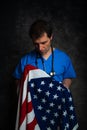 Pensive/sad doctor holding the American flag.