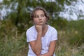 Pensive sad teenager girl looks to the side. Portrait in the park outdoors. Emotions, feelings concept. Blurred background