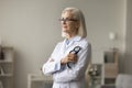 Pensive senior elder doctor woman in glasses and uniform coat