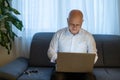 Pensive senior man reading news on laptop. Cheerful excited mature male using portable computer at home, copy space. Royalty Free Stock Photo