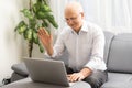 Pensive senior man reading news on laptop. Cheerful excited mature male using portable computer at home, copy space. Royalty Free Stock Photo